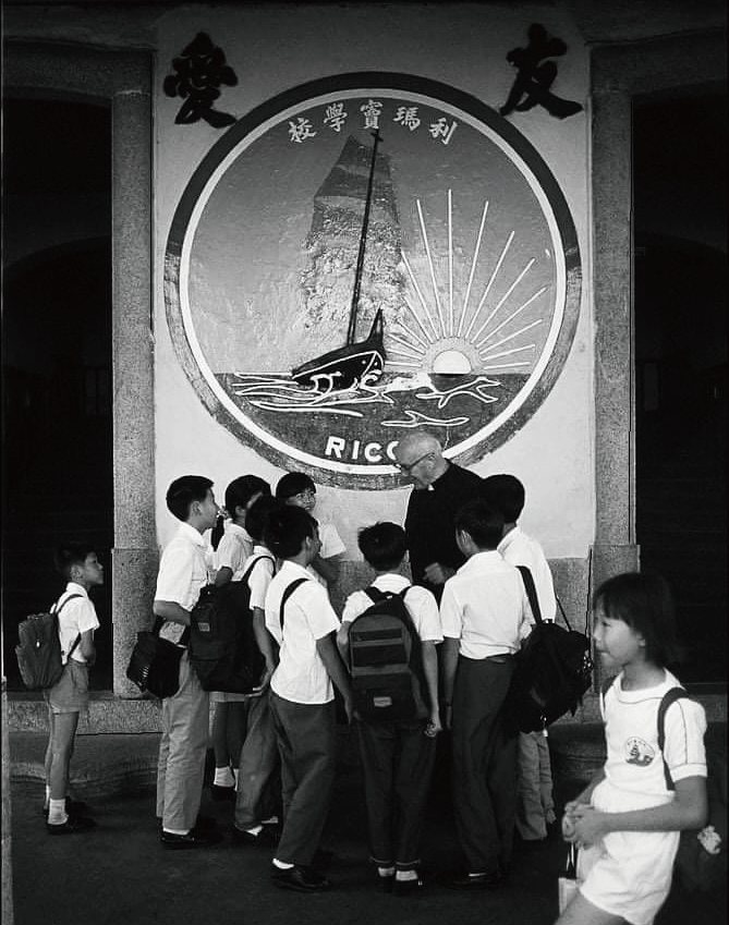 學生在校徽壁畫前聆聽神父講解